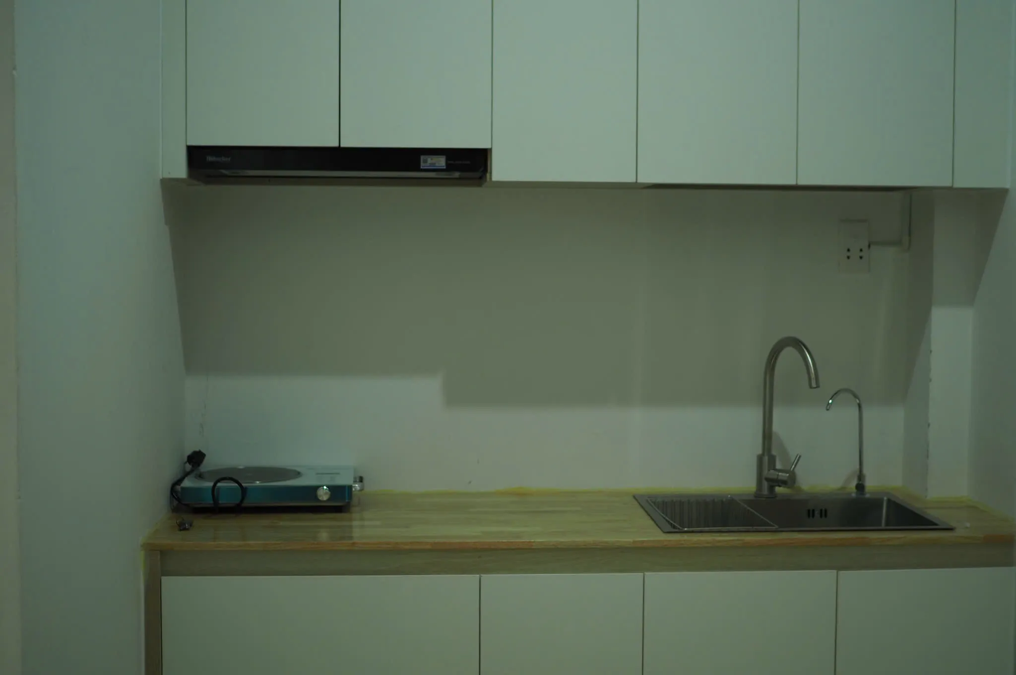 Bếp studio với tủ trắng, bếp từ và bồn rửa