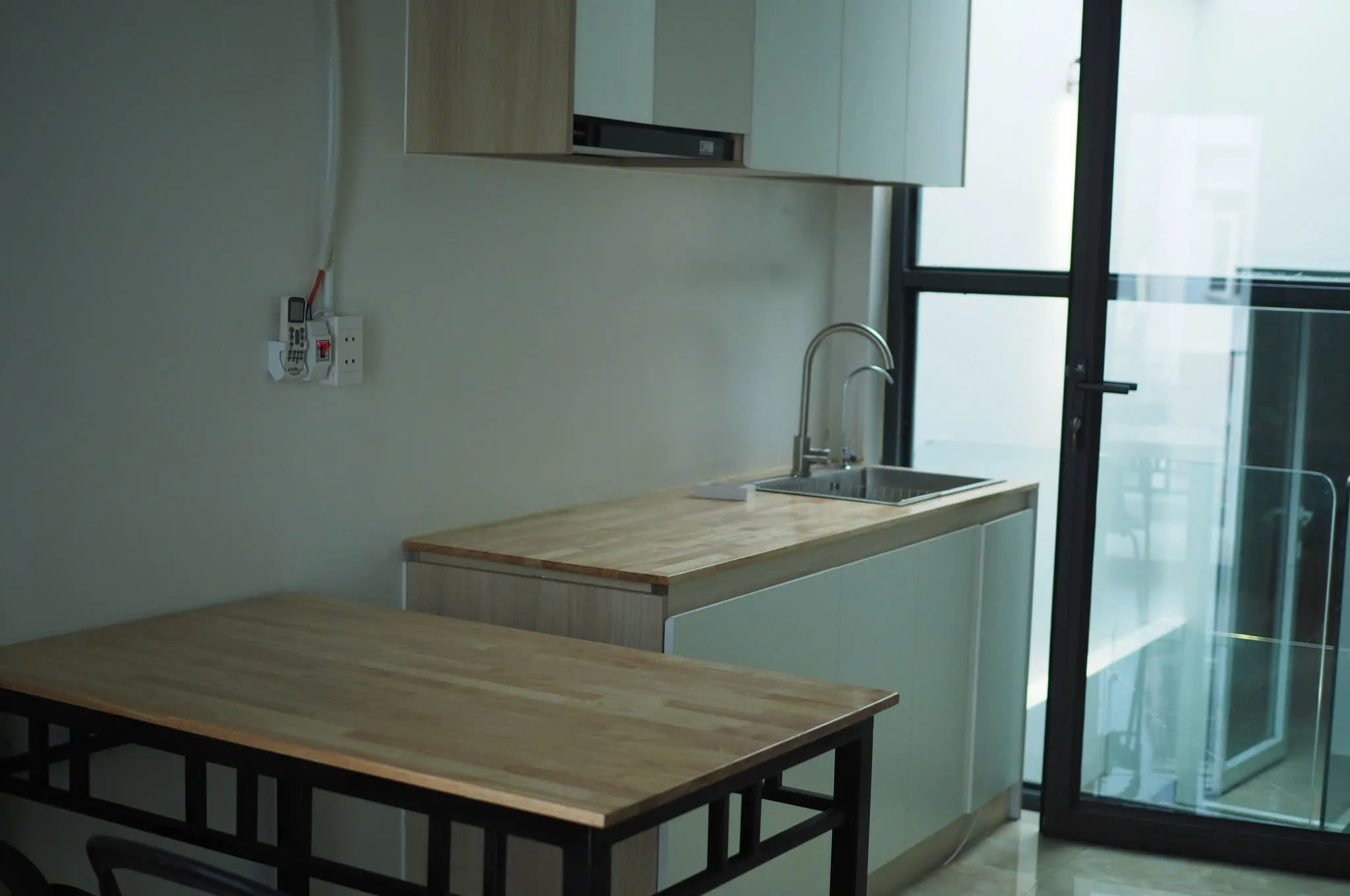 Bếp hẹp, bàn ăn gỗ và cửa kính lớn