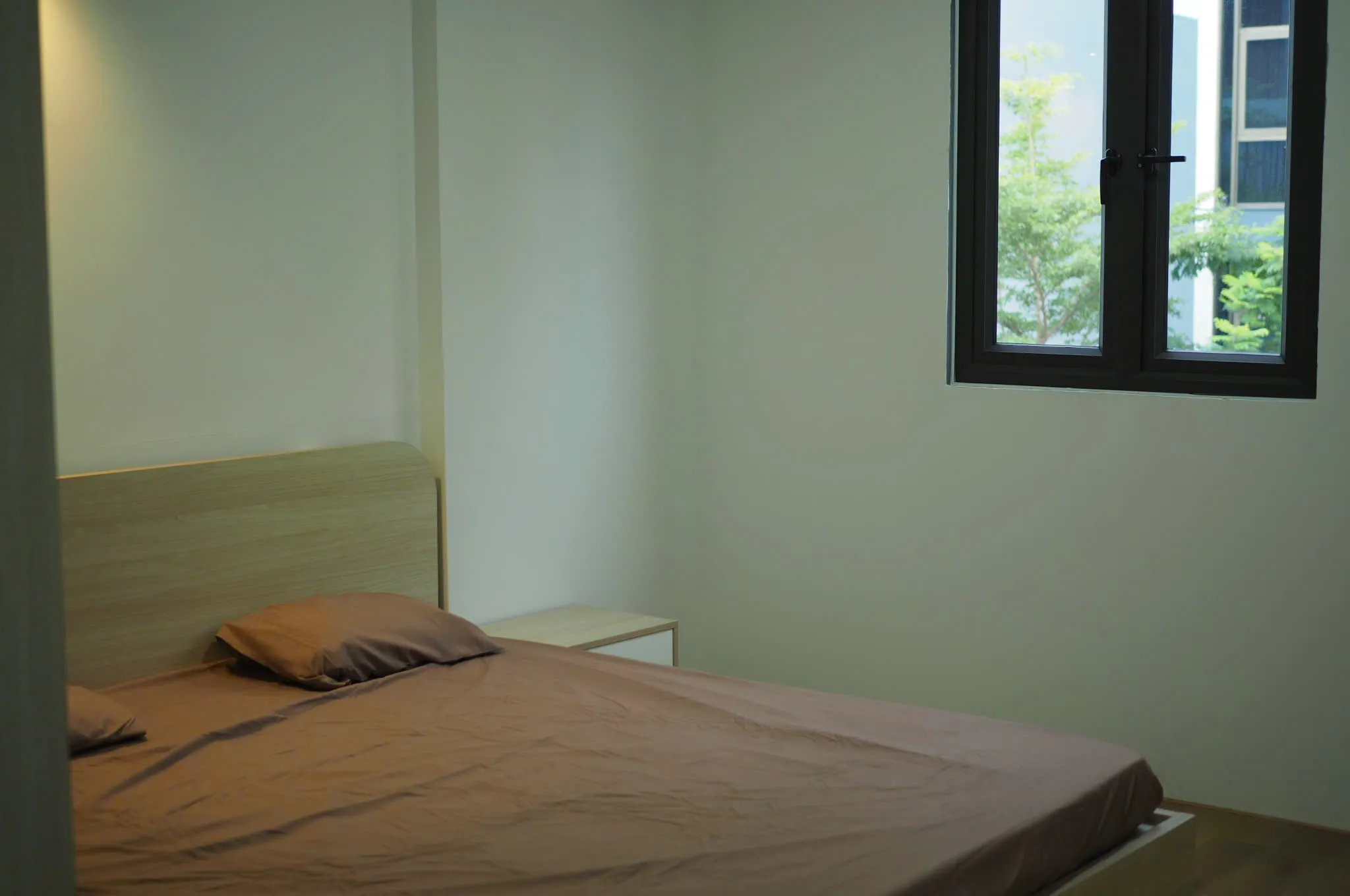 Phòng ngủ studio, giường và cửa sổ nhìn cây