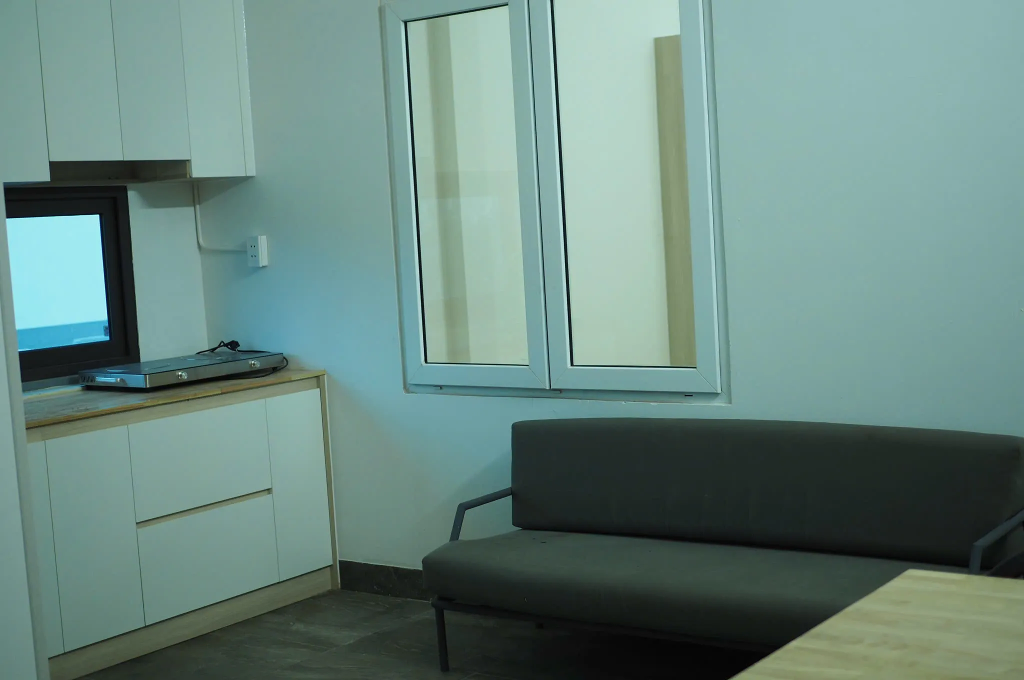 Sofa xám cạnh tủ bếp trắng
